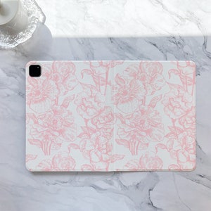 May include: A white tablet case with a pink floral pattern. The case has a cutout for the camera lens.