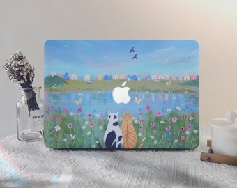 Könnte beinhalten: Eine Laptop-Haut mit einem gemalten Design einer Meereslandschaft mit bunten Häusern, einem See und zwei Katzen, die auf einer Blumenwiese sitzen. Das Design ist im verspielten Stil mit blauem Himmel und weißen Wolken gehalten.