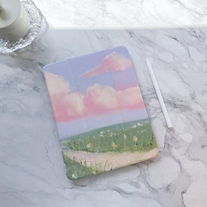 May include: A pink and purple painted iPad case with a landscape scene of a field with a path and white flowers. The sky is painted with pink and white clouds.