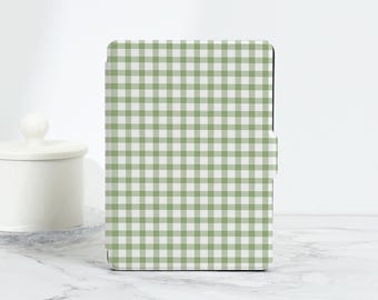 Puede incluir: Funda para tableta con estampado de cuadros vichy verdes y blancos, con cierre magnético. La funda rectangular está sobre una superficie de mármol blanco. Un tarro de cerámica blanco con tapa en el fondo.