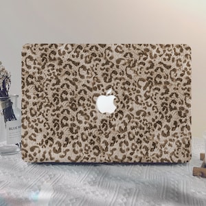 May include: A laptop computer with a brown and beige leopard print skin. The Apple logo is visible on the back of the laptop.
