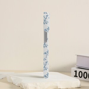 May include: A white phone case with a blue floral pattern. The case is made of a hard plastic material and has a raised edge to protect the screen.