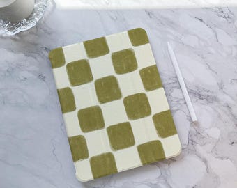 May include: An olive green and white checkered tablet case with a matching stylus. The case is rectangular with rounded corners. The background is a marble surface.