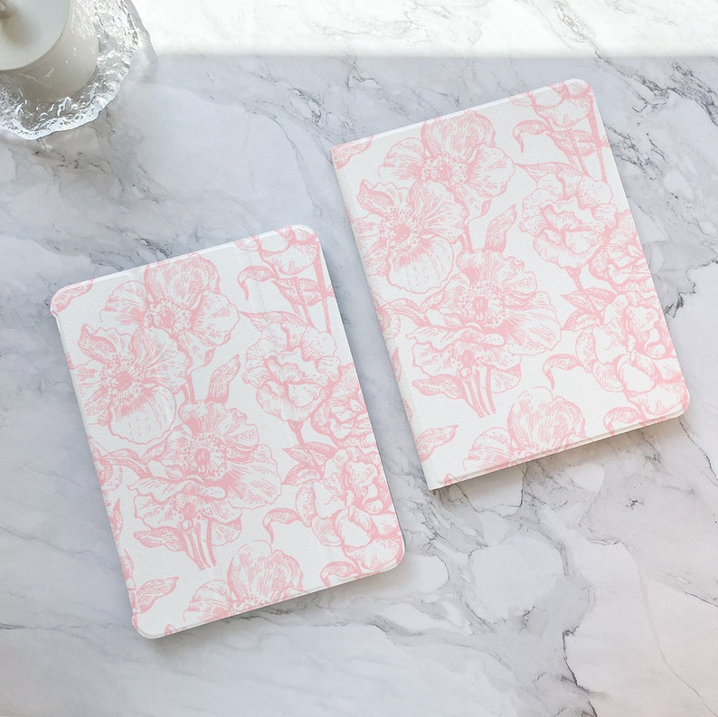 May include: Two pink floral patterned covers for tablets or notebooks. The covers are made of a white material with a pink floral design.