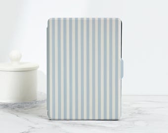 Puede incluir: Una funda para tableta con diseño de rayas verticales en azul claro y blanco. La funda tiene rayas verticales y un cierre de lengüeta azul claro. Se encuentra sobre una superficie de mármol blanco.