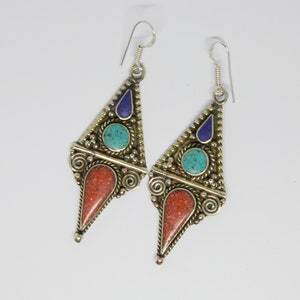 May include: A pair of silver dangle earrings with turquoise, coral, and lapis lazuli stones. The earrings are in the shape of a triangle with a pointed bottom.