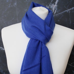 May include: A royal blue scarf made of soft fabric. The scarf is folded and draped around a white mannequin's neck.