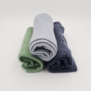 May include: Three rolled up fabric swatches in green, light blue, and dark blue.