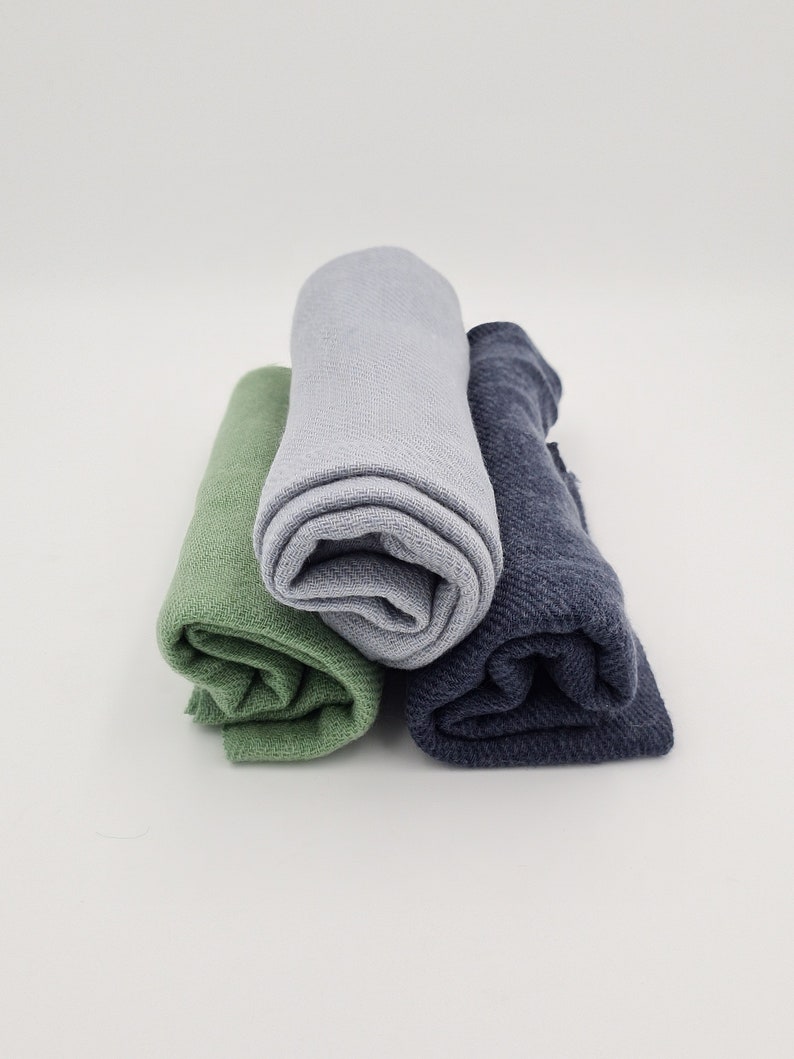 May include: Three rolled up fabric swatches in green, light blue, and dark blue.