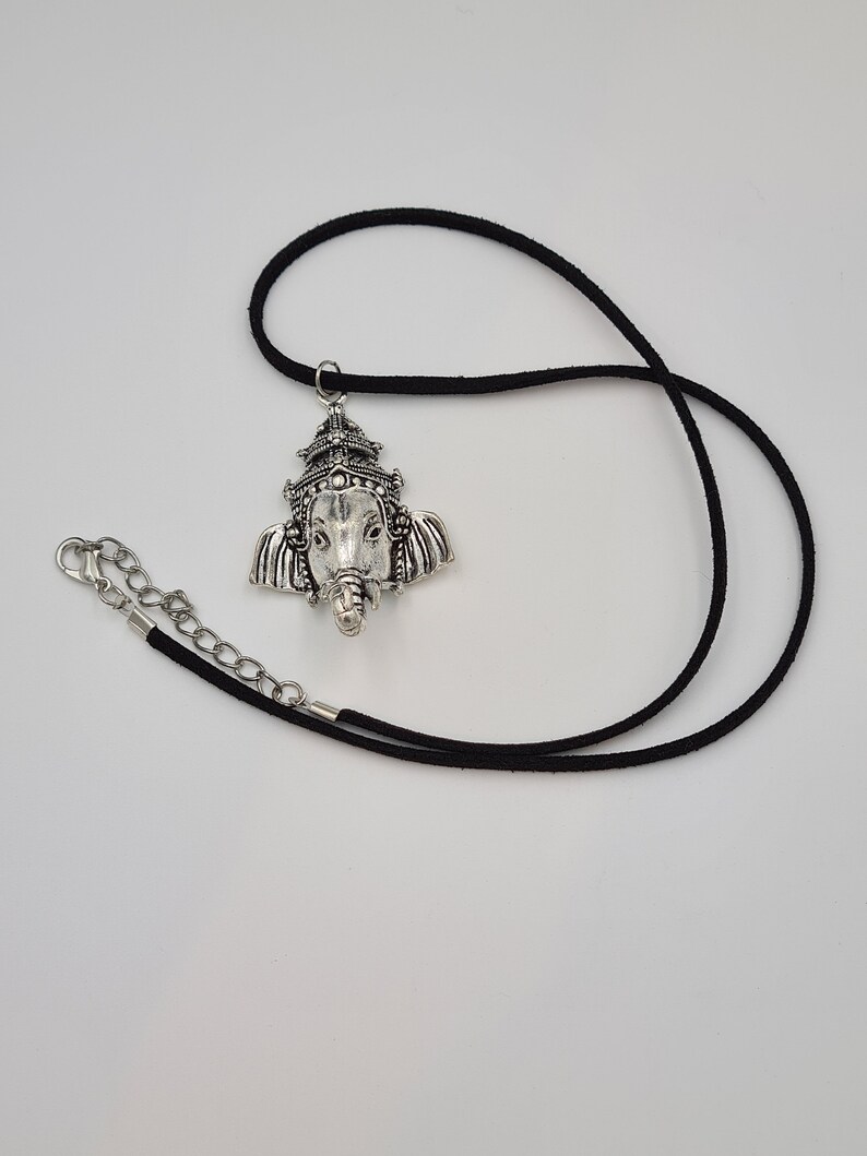 Op de afbeelding: Een zilveren ketting met een hanger met het gezicht van de hindoe&iuml;stische god Ganesha. De hanger is bevestigd aan een zwart koord.