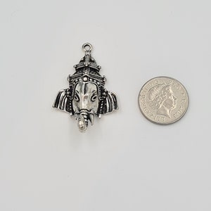 Op de afbeelding: Zilveren bedelhanger met een gedetailleerde afbeelding van de hindoe-god Ganesha, met een kroon en een olifantenkop. De bedel wordt getoond naast een Britse munt van &eacute;&eacute;n pond ter vergelijking van de grootte.