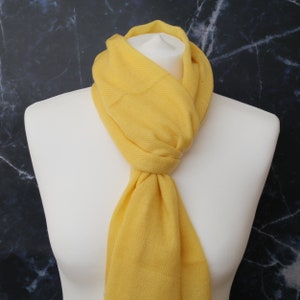 May include: A bright yellow scarf made of soft fabric. The scarf is draped around a white mannequin's neck.
