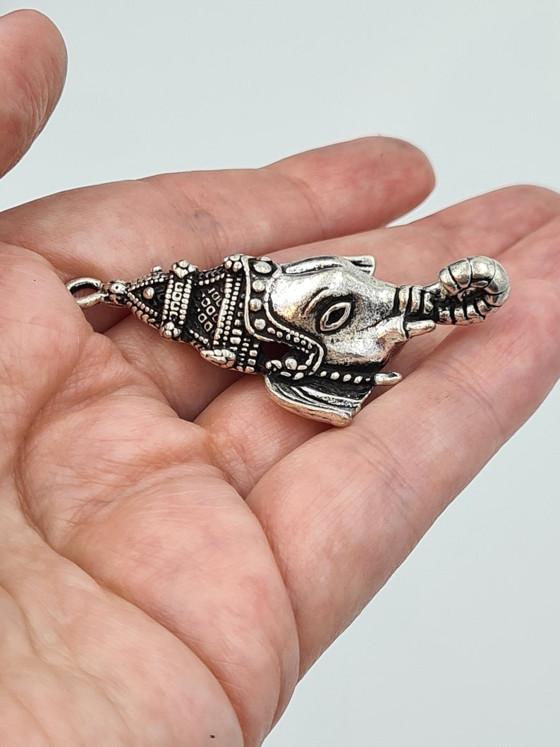 Op de afbeelding: Zilveren olifant bedel met ingewikkelde details en een getextureerd oppervlak. De bedel is gevormd als een olifantenkop met een slurf en oren.