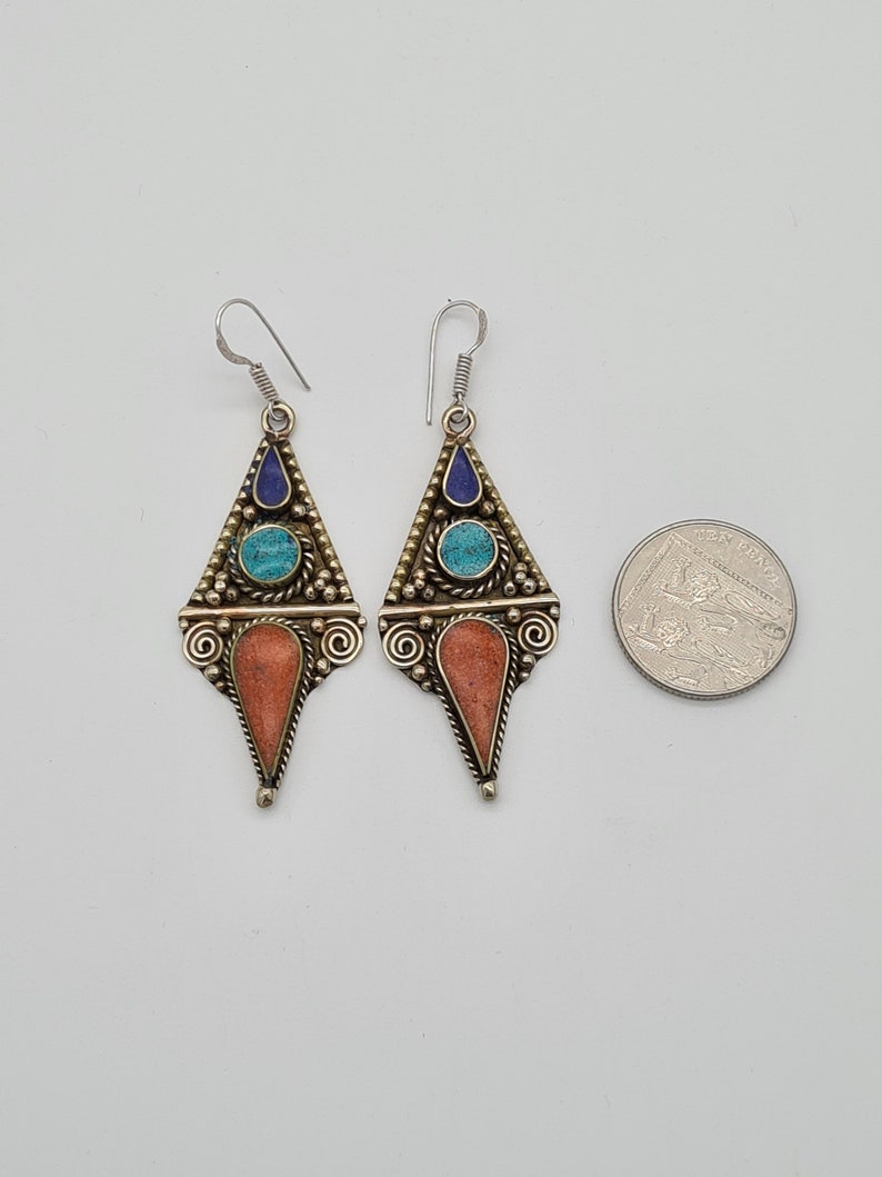 May include: A pair of dangle earrings with a triangular design. The earrings are made of silver and feature turquoise and lapis lazuli stones.