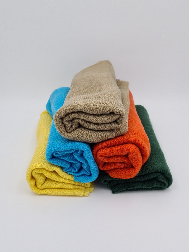 May include: A stack of four rolled fabric swatches in different colors: yellow, blue, orange, and green.