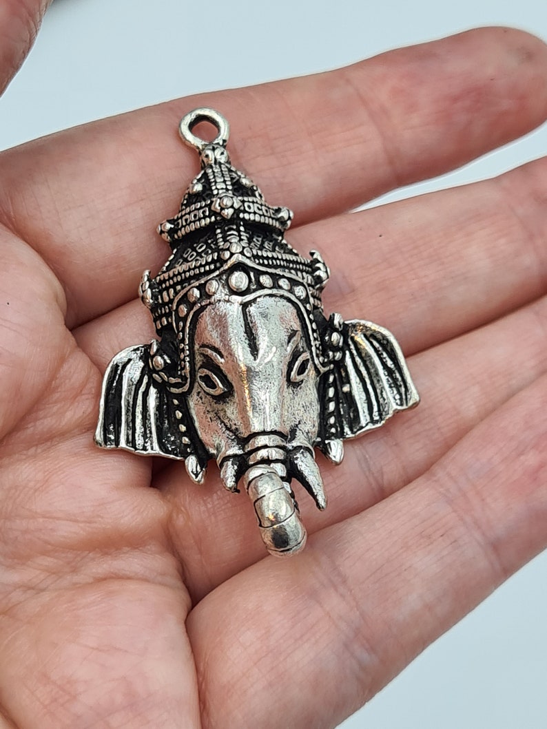 Op de afbeelding: Zilveren hanger met een gedetailleerde afbeelding van de hindoe-god Ganesha, met een kroon en een olifantenkop.