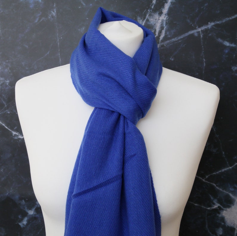 May include: A royal blue scarf made of soft fabric. The scarf is folded and draped around a white mannequin's neck.