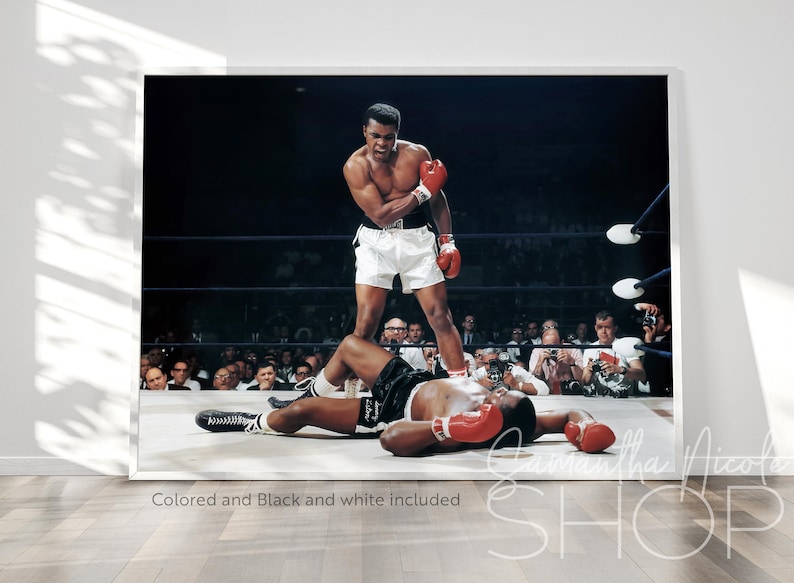 Puede incluir: Una fotograf&iacute;a en blanco y negro de un combate de boxeo. Un boxeador con pantalones cortos blancos se encuentra sobre un boxeador que est&aacute; en el suelo. El boxeador en el suelo lleva pantalones cortos negros y un guante de boxeo rojo. La multitud est&aacute; viendo el combate.