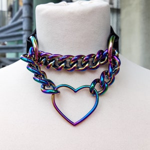 Op de afbeelding: Een regenboogkleurige, iriserende ketting choker met een hartvormige hanger. De ketting is dik en stevig, en het hart is groot en open.