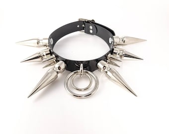 May include: A black leather choker with silver spikes and a silver ring. The choker is a punk rock style accessory.