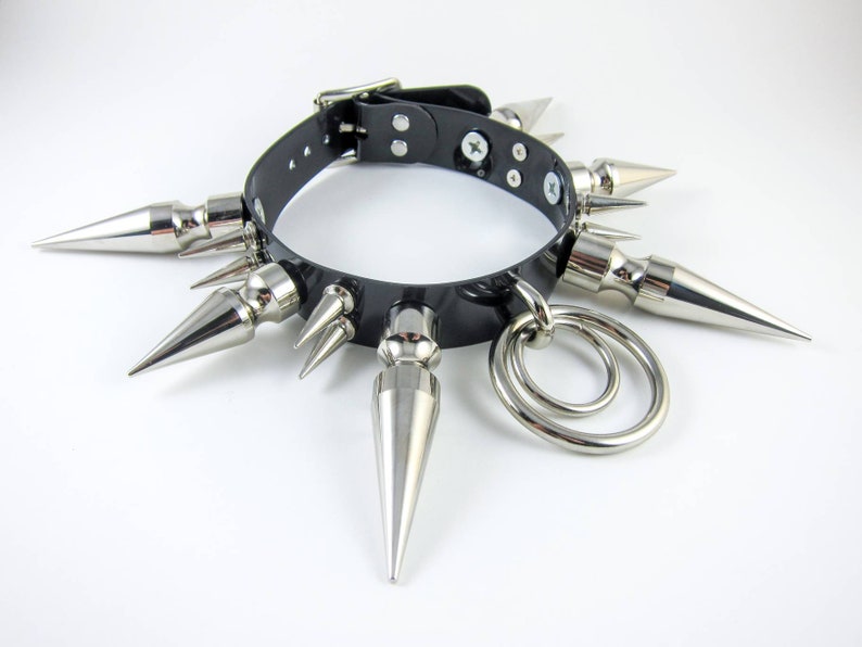 May include: A black leather choker with silver spikes and a double ring pendant.
