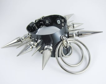 May include: A black leather choker with silver spikes and three silver rings attached. The choker is a punk rock style accessory.