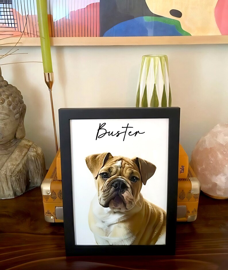 May include: A framed portrait of a bulldog with the name "Buster" in script. The dog has a tan and white coat, with a wrinkled face and floppy ears. The frame is black, and the background is white.