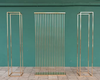 May include: Three gold metal free-standing dividers with a geometric design. The dividers are made of thin vertical bars and are arranged in a row.