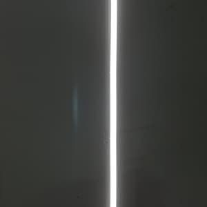 K&ouml;nnte beinhalten: Nahaufnahme einer wei&szlig;en vertikalen Lichtlinie vor einem dunkelgrauen Hintergrund.