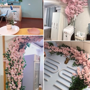 Pu&ograve; includere: Un collage di immagini che mostrano l'interno di un'azienda decorato con ghirlande di fiori di ciliegio rosa. Le ghirlande sono utilizzate come elemento decorativo su pareti e soffitto. Le ghirlande sono fatte di fiori e rami artificiali.