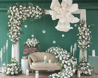 Puede incluir: Decoración de ceremonia de boda con un sofá beige, arreglos florales y velas. Un letrero de madera dice "Welcome to our Wedding". Una gran flor de papel y globos de cristal colgantes se suman a la decoración. El fondo es verde teal.