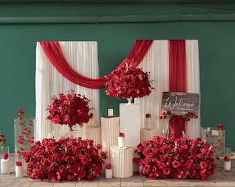 May include: A wedding ceremony setup featuring red roses and white drapery. The scene includes floral arrangements, candles, and a wooden sign that reads "Welcome to our Wedding."