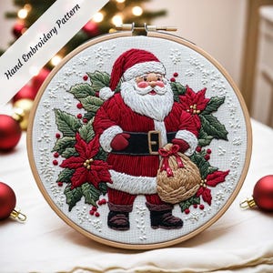 May include: Embroidered hoop art featuring Santa Claus holding a sack of gifts. He is surrounded by poinsettia flowers, holly, and snowflakes. The background is white.