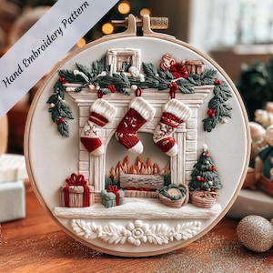 Könnte beinhalten: Ein runder Stickrahmen mit einem weihnachtlichen Design. Das Design zeigt einen Kamin mit drei hängenden Strümpfen, Geschenken, einem Weihnachtsbaum und dem Text "Hand Embroidery Pattern". Die Farbpalette umfasst Rot, Weiß und Grün.