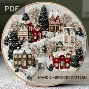May include: A hand-embroidered winter village scene in a round wooden hoop. The artwork features snow-covered houses in red, green, and white, surrounded by evergreen trees and bare winter trees. The text "PDF" and "HAND EMBROIDERY PATTERN" are visible.