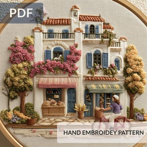 以下が含まれることがあります： 手刺繍のヨーロッパの村のシーンのパターン。赤い瓦屋根、青いシャッター、ピンクの花のつるが特徴の建物の詳細な描写が特徴です。「PDF」と「HAND EMBROIDEY PATTERN」の文字が表示されます。