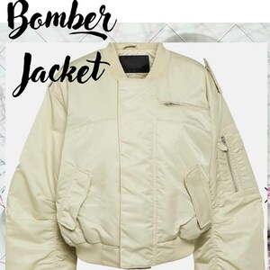 May include: Cream-colored bomber jacket with a ribbed collar and cuffs. Features a zip closure, two front pockets, and a small pocket on the left sleeve. The words "Bomber Jacket" and "Digital Patterns" are written on the image.