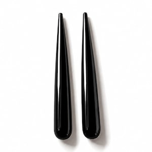 May include: Two identical, long, slender, and tapered objects with a smooth, glossy black finish. Each piece features a rounded base that gradually narrows to a fine, pointed tip, creating a sleek, elongated silhouette with reflective surfaces.