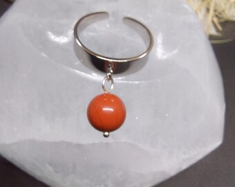May include: A silver adjustable ring with a dangling red gemstone bead.