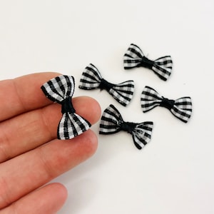 May include: Six black and white gingham ribbon bows. The bows are tied with black ribbon and are approximately 1 inch in size.