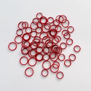May include: A pile of red rubber bands on a white background.