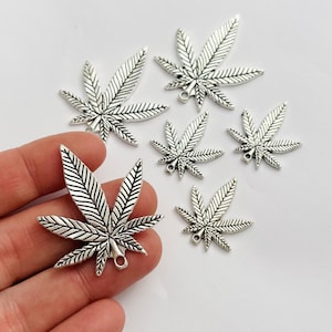 May include: Six silver-toned marijuana leaf charms with a loop at the top for attaching to jewelry or other crafts.