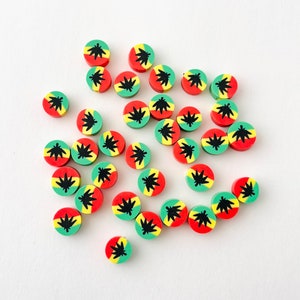 May include: A collection of round, colorful, resin beads with a black marijuana leaf design. The beads are red, green, and yellow.