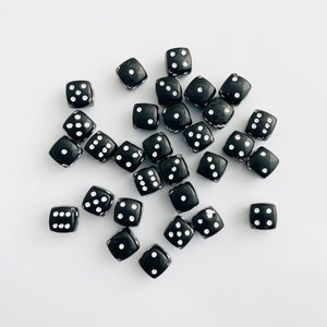 May include: A group of black dice with white dots on a white background. The dice are scattered randomly.