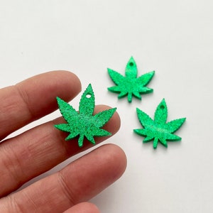 May include: Three green glitter marijuana leaf charms with a hole at the top for hanging.