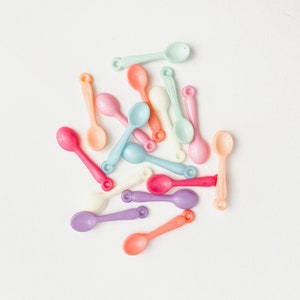 May include: A collection of pastel-colored plastic spoons. The spoons are in shades of pink, blue, green, and yellow.