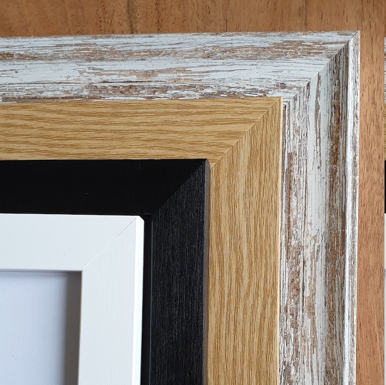 Op de afbeelding: Close-up van een meerlaags fotolijst met een witte, zwarte, bruine en verweerde witte afwerking.