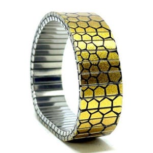 May include: A gold and black honeycomb patterned watch strap with a silver-coloured, expandable strap. The watch strap is shown against a white background.