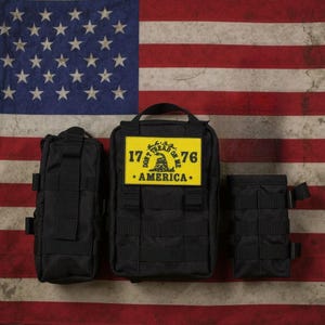 May include: Three black tactical pouches with a yellow patch on the center pouch. The patch features the text "1776 AMERICA" and a coiled snake design. The background is an American flag.