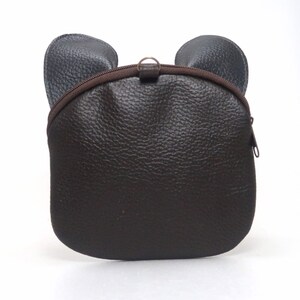 K&ouml;nnte beinhalten: Eine braune Lederhandtasche mit B&auml;renohren. Die Tasche hat einen Rei&szlig;verschluss und einen braunen Rei&szlig;verschluss-Schieber.